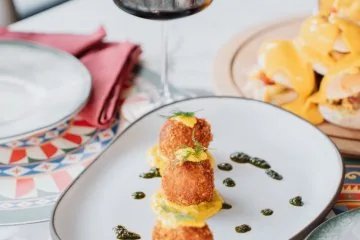 A plated dish and drinks beside the windows at Fiaba Brasserie